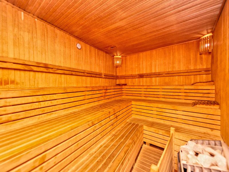 Saunaraum im Kirman Leodikya Resort Hotel mit Holzbänken und einer Wanduhr.