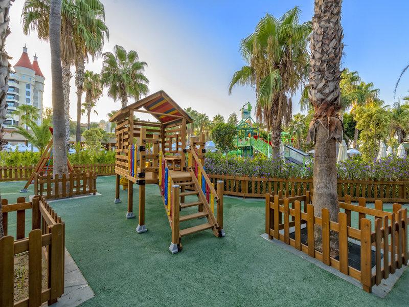 Kinderspielplatz im Kirman Leodikya Resort mit Holzspielhaus und Rutsche