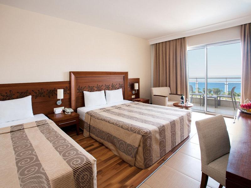 Zwei Doppelbetten in einem Hotelzimmer mit Meerblick, einem Schreibtisch und einem Balkon.