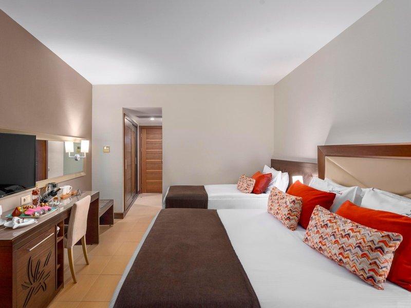 Innenansicht eines Hotelzimmers im Kirman Leodikya Resort mit zwei Betten und Dekor.