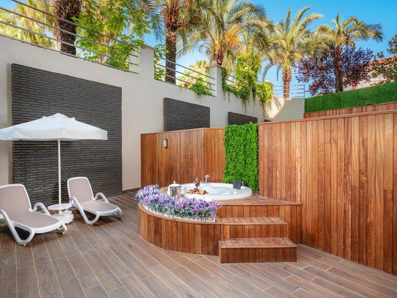 Jacuzzi auf der Terrasse des Kirman Leodikya Resorts mit zwei Liegen und einem Schirm