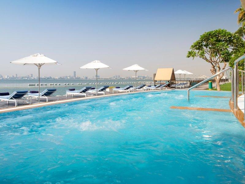 Außenpool mit Sonnenliegen und Sonnenschirmen im Sheraton Doha Resort Convention Hotel
