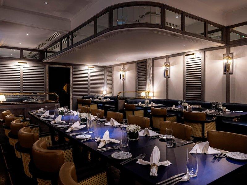 Innenansicht des Restaurants im Sheraton Doha Resort Convention Hotel mit langen Tischen, Lederstühlen und Tischdekorationen.