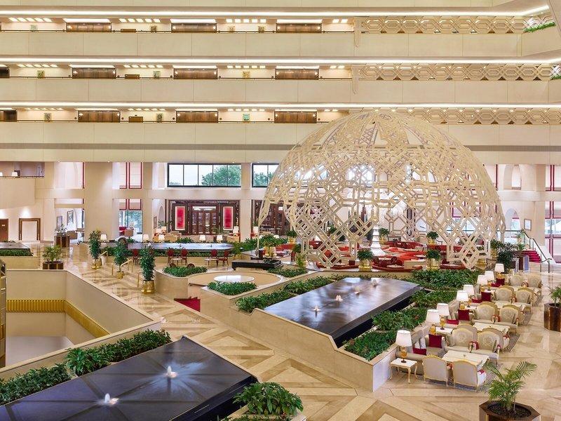 Innenansicht des Sheraton Doha Resort Convention Hotel mit einer großen Struktur und mehreren Sitzbereichen.