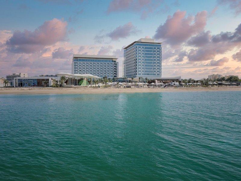 Außenansicht des Rixos Gulf Hotel Doha am Strand bei Sonnenuntergang