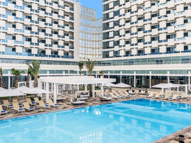 Außenbereich des Rixos Gulf Hotel Doha mit Pool, Liegen und Sonnenschirmen
