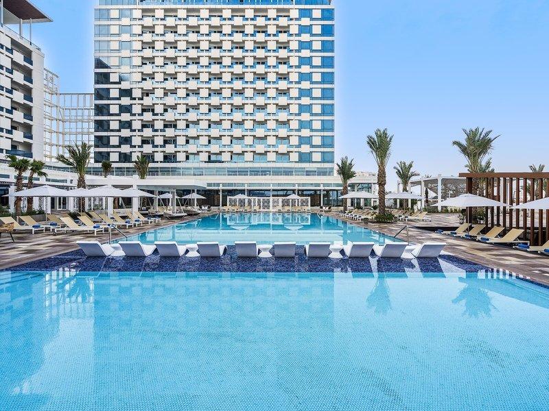 Rixos Gulf Hotel Doha mit großem Swimmingpool und Liegestühlen unter Sonnenschirmen