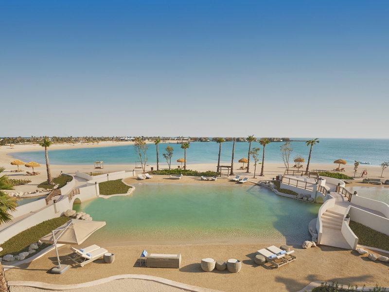 Luftaufnahme des Banana Island Resorts Doha von Anantara mit Strand, Pool und Palmen