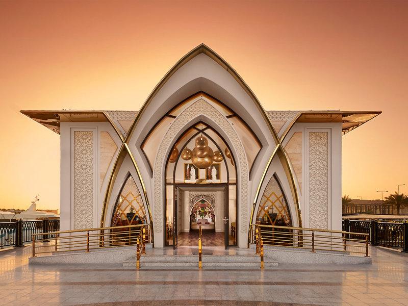 Außenansicht des Banana Island Resorts Doha mit goldenen Details und offenem Eingang.