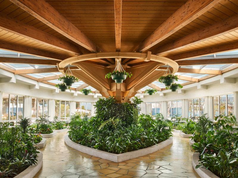 Innenansicht der Lobby des Banana Island Resort Doha by Anantara mit Holzdecken, Pflanzen und Glaswänden.