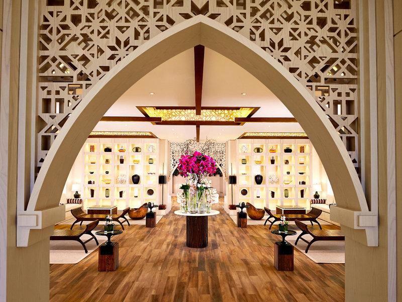 Lobby des Banana Island Resorts Doha von Anantara mit Holzboden und gemusterten Wänden.