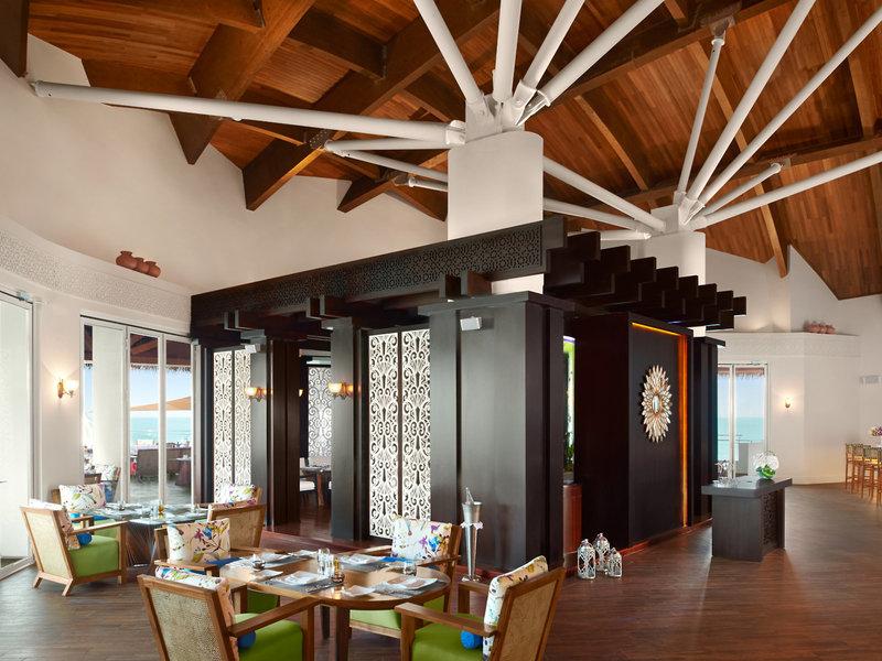 Innenbereich des Banana Island Resorts Doha von Anantara mit Holzboden, modernen Möbeln und Blick auf das Meer.