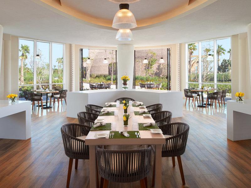 Innenansicht des Restaurants im Banana Island Resort Doha von Anantara mit großen Fenstern und hölzernem Boden.