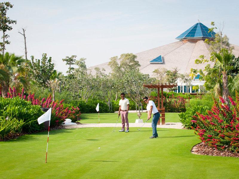 Zwei Männer spielen Golf auf dem Golfplatz des Banana Island Resorts Doha von Anantara.