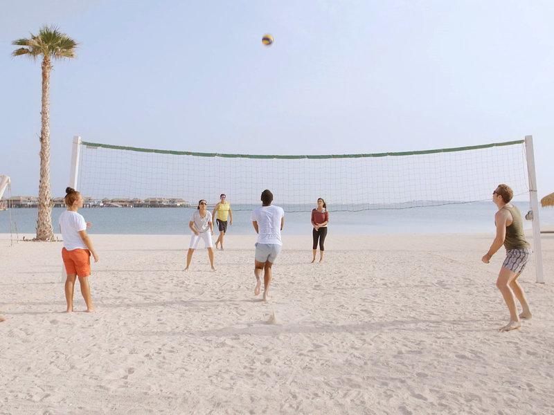 Gruppe spielt Volleyball am Strand des Banana Island Resorts in Doha.