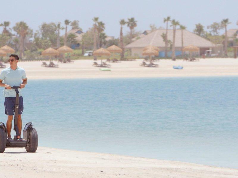 Fahrer auf einem Segway an der Strandlinie des Banana Island Resorts Doha von Anantara.