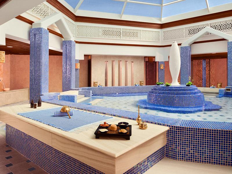 Innenansicht des Wellnessbereichs im Banana Island Resort Doha by Anantara mit blauen Mosaiken und einer zentralen Wasserfläche.