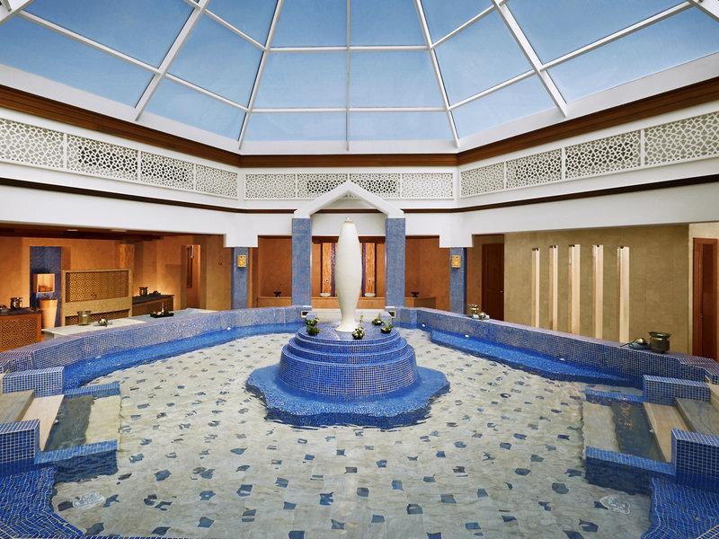 Innenansicht des Pools im Banana Island Resort Doha von Anantara mit Glasdach, blauen Fliesen und zentraler Vase.