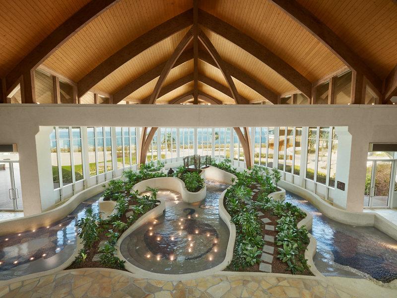 Innenansicht des Wassergartens im Banana Island Resort Doha von Anantara mit Pflanzen und Wasserfällen.