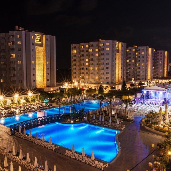 Nachtansicht des Grand Park Lara Hotels mit beleuchtetem Swimmingpool und Gästebereichen.