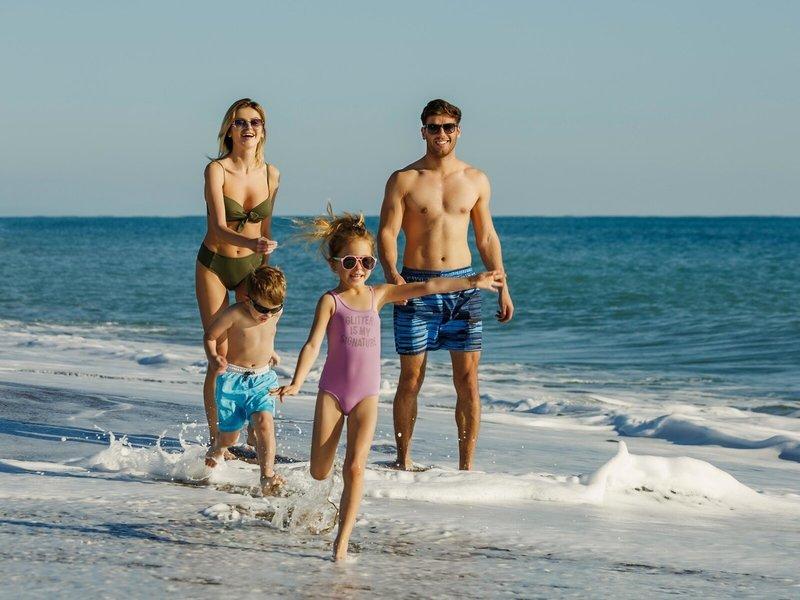 Familie am Strand vor dem Grand Park Lara Hotel, alle in Badekleidung und sonnigem Wetter