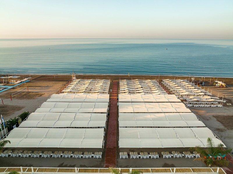 Luftaufnahme des Grand Park Lara Hotels mit Strand und vielen Sonnenschirmen und Liegen.
