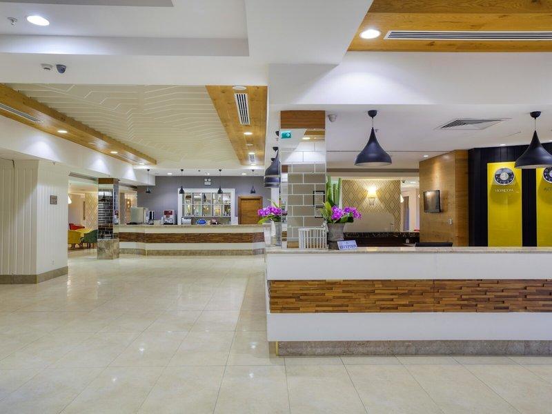 Reception des Grand Park Lara Hotels mit Blumenarrangements und moderner Einrichtung.