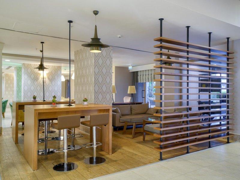 Innenbereich des Grand Park Lara Hotels mit modernem Essbereich und Holzmöbeln.