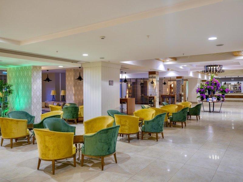 Lobby des Grand Park Lara Hotels mit farbenfrohen Sesseln und einem großen Blumenstrauß.