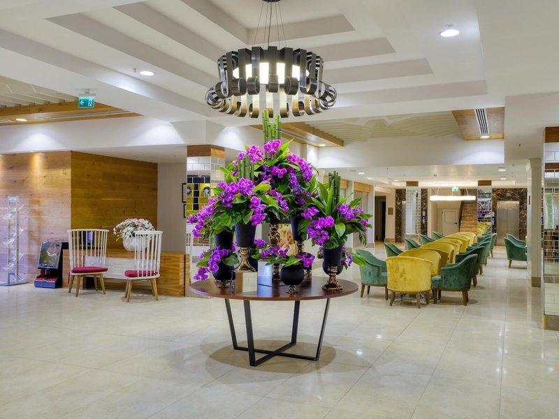 Lobby des Grand Park Lara Hotels mit Tisch, Blumen und Stühlen