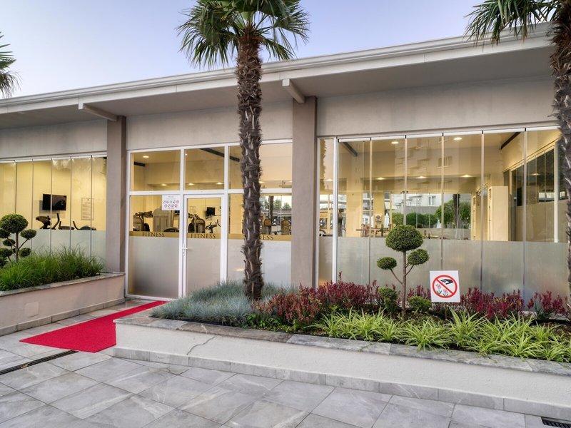 Außenansicht des Fitnesscenters des Grand Park Lara Hotels mit rotem Teppich und Palmen