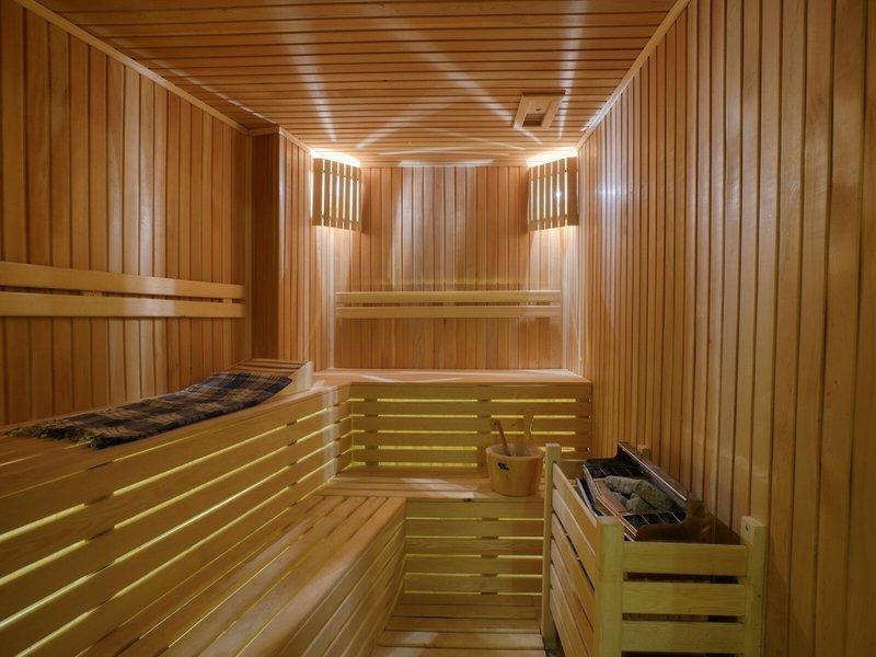 Innenansicht einer Holzsauna mit Liegeflächen, Holzeimer und Holzregale.