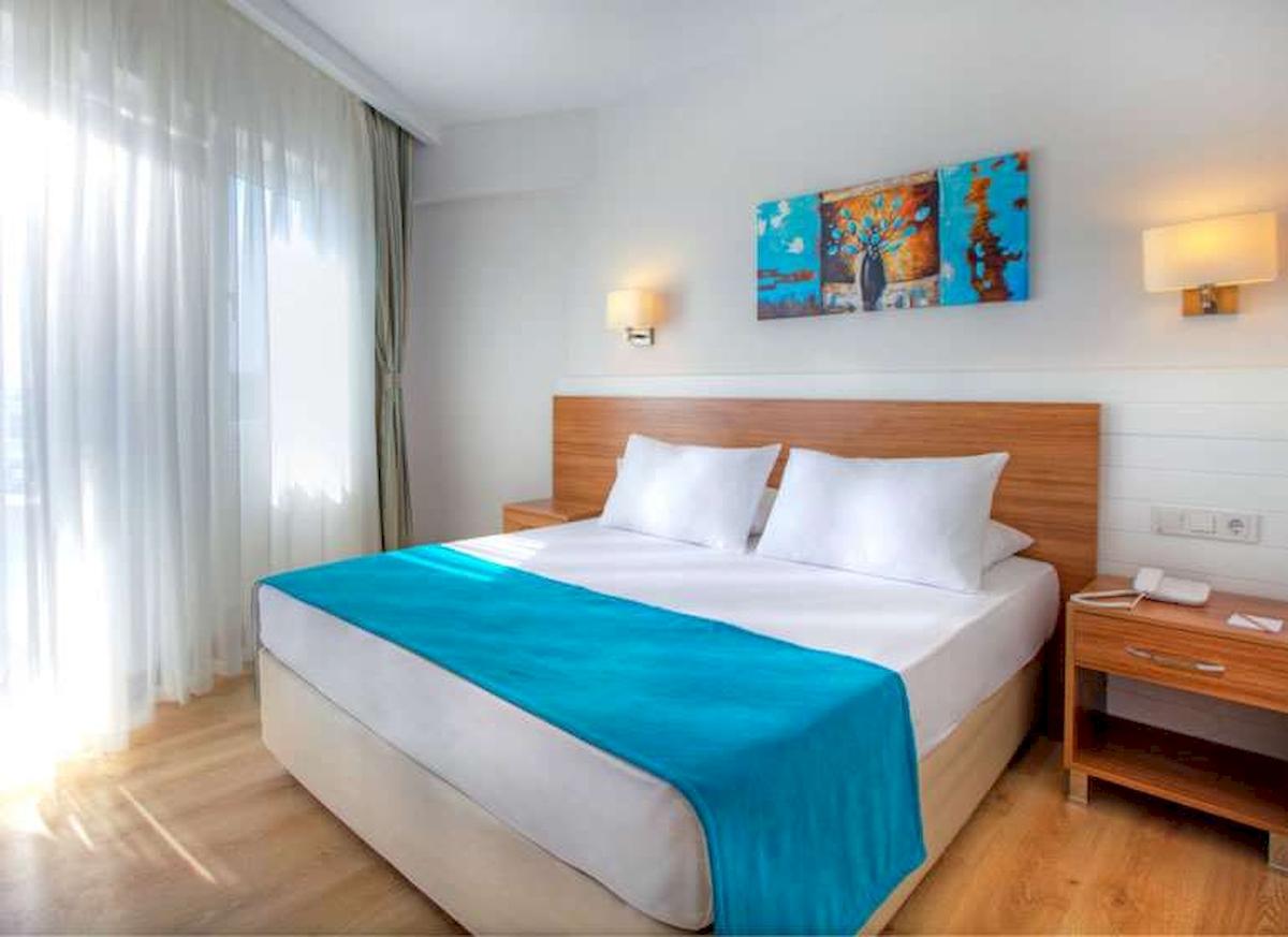 Ein elegantes Hotelzimmer im Grand Park Lara mit einem Bett, blauer Decke, weißen Kissen und Kunst an der Wand.