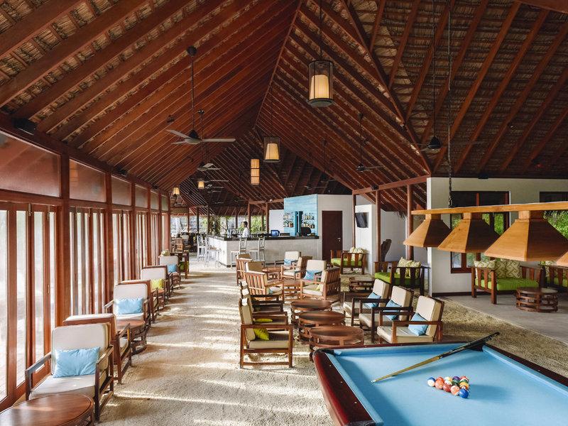 Hotellounge des Summer Island Maldives mit Billardtisch, Holzmöbeln und einer Bar.