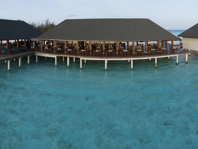 Luftaufnahme des Summer Island Maldives Hotels mit Restaurant am Wasser und Gästen.