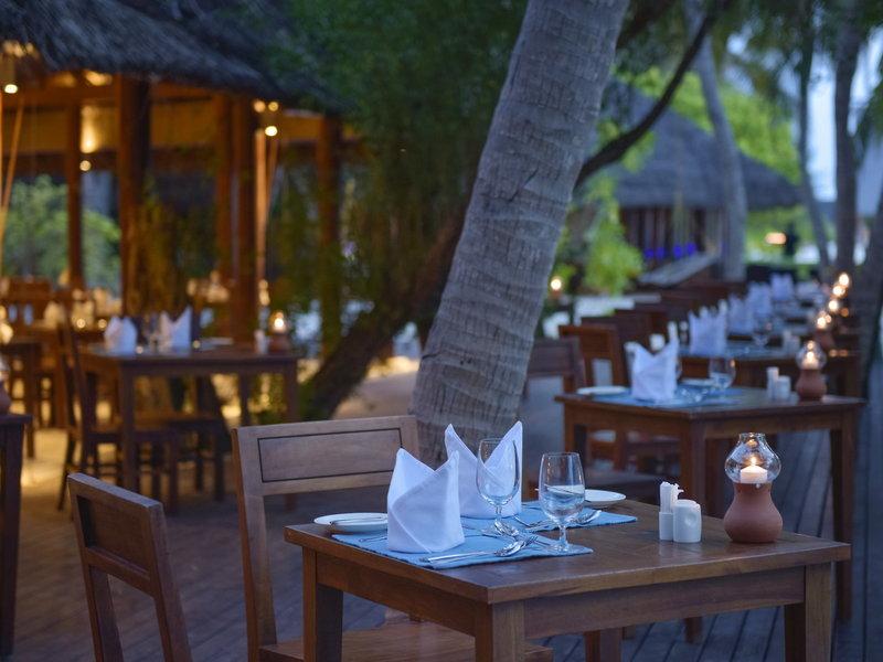 Außenbereich des Summer Island Maldives Resorts mit gedeckten Tischen und Kerzen.