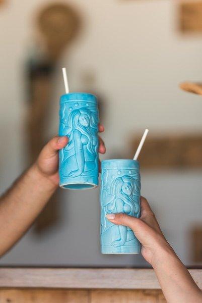 Zwei Personen halten türkisfarbene Becher mit Strohhalmen.