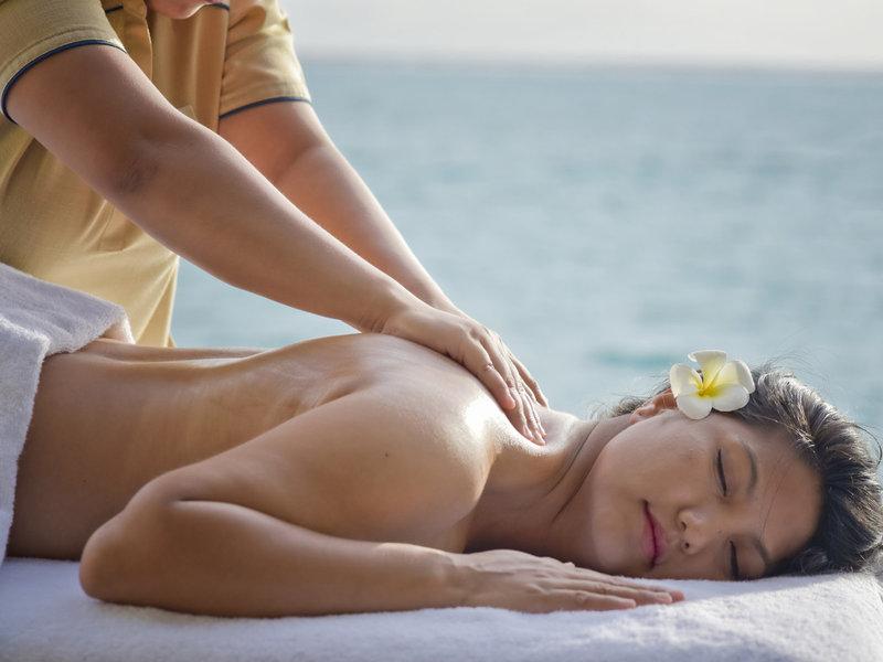 Eine Frau genießt eine Massage am Strand im Sommer Island Maldives Hotel.