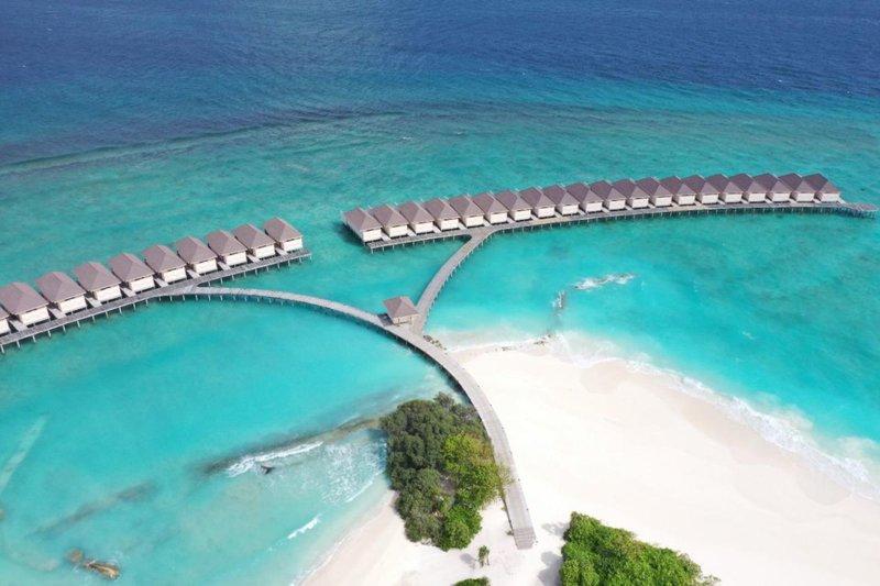 Luftaufnahme des Brennia Kottefaru Maldives Hotels mit Wasserbungalows und Brücke am Strand