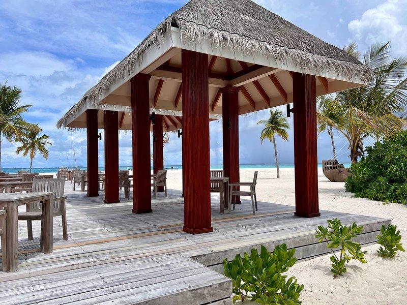 Pavillon mit Tischen und Stühlen auf dem Strand des Brennia Kottefaru Maldives