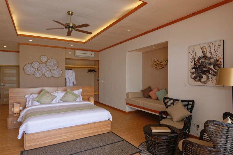 Innenansicht des Schlafzimmers im Brennia Kottefaru Maldives Hotel mit einem großen Bett, Möbeln und einer Klimaanlage.