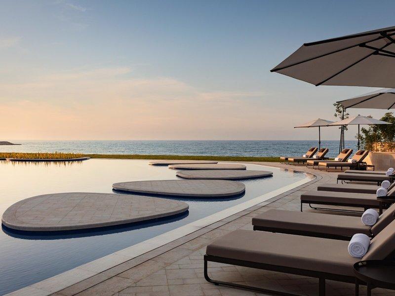 Poolseite des St. Regis Al Mouj Muscat Resorts mit Blick auf den Ozean