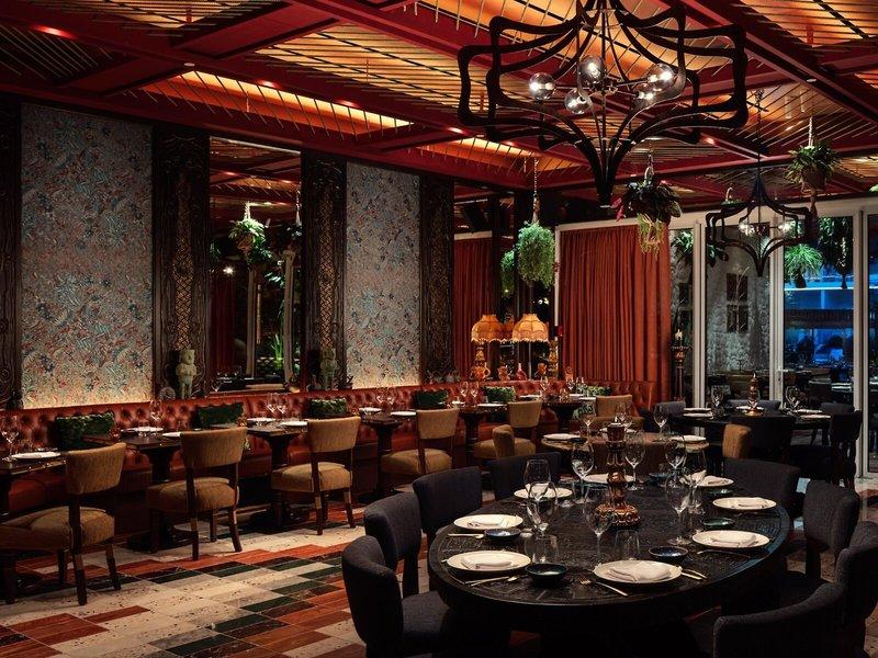 Innenraum des Restaurants im St. Regis Al Mouj Muscat Resort mit Tisch- und Stuhlarrangements.