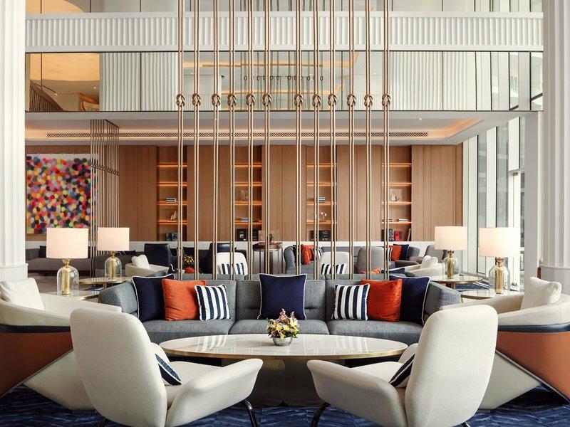 Lobby des St. Regis Al Mouj Muscat Resorts mit Sofas, Lampen und Kunstwerk.