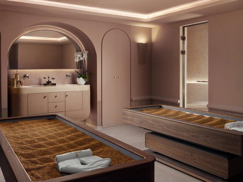 Spa-Behandlungsraum im St. Regis Al Mouj Muscat Resort mit zwei Behandlungsbetten und einer weißen Kommode.