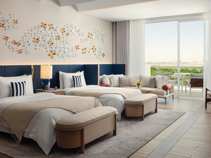 Doppelzimmer im St. Regis Al Mouj Muscat Resort mit zwei Betten und Blick auf den Garten.
