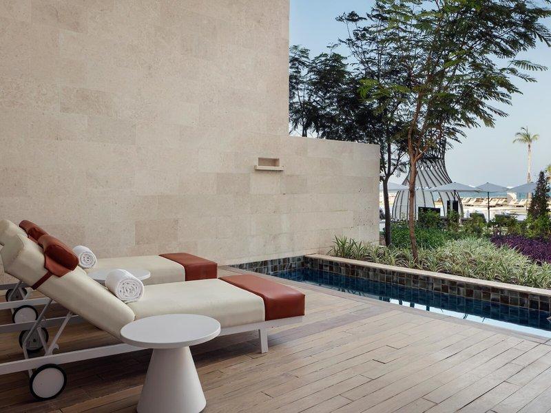 Lounge-Bereich des St. Regis Al Mouj Muscat Resorts mit Swimmingpool und Liegen