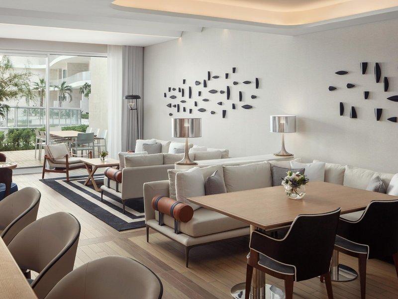 Loungebereich im St. Regis Al Mouj Muscat Resort mit weißen Möbeln und Dekoration.