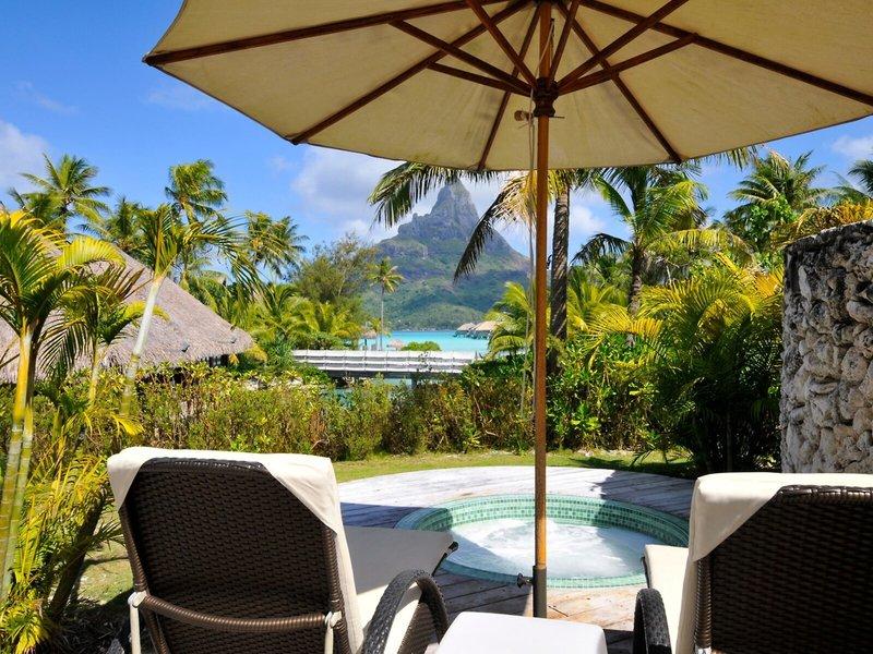 Außenbereich des InterContinental Bora Bora Resorts mit zwei Loungestühlen und einem Sonnenschirm.