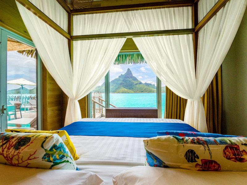 Ein Bett in einem Hotelzimmer mit Aussicht auf den Berg und das Meer.